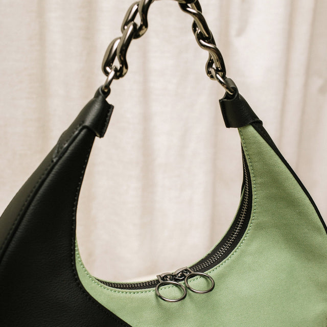 Close up detail of the green Mariah Bag by Brinn with its cute circle zipper pulls above the green organic cotton