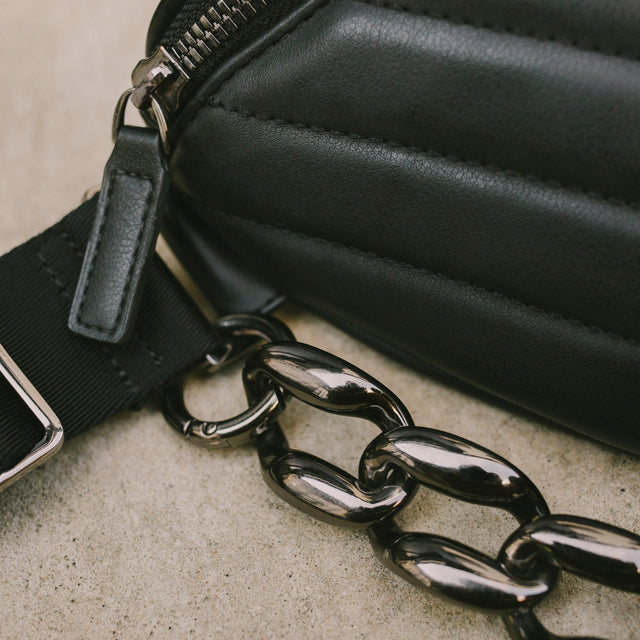 Detailed shot of black faux leather on the quilted Honeypie Bum Bag and the gunmetal chain accessory